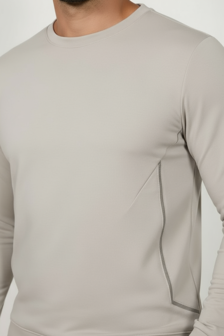 Beige long-sleeve shirt worn by a person on a white background